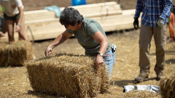 Person measuring for fit in straw bale construction.