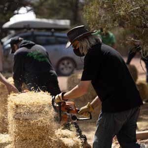Man using chainsaw to cut and trim strawbales for use in a house.