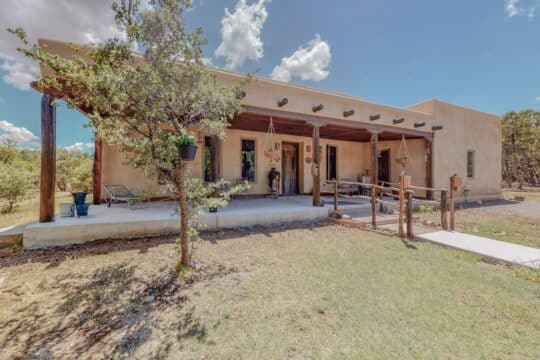 Strawbales house for sale in New Mexico, front entry with tree and porch