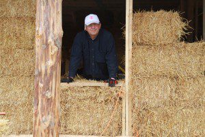 man behind straw bale wall