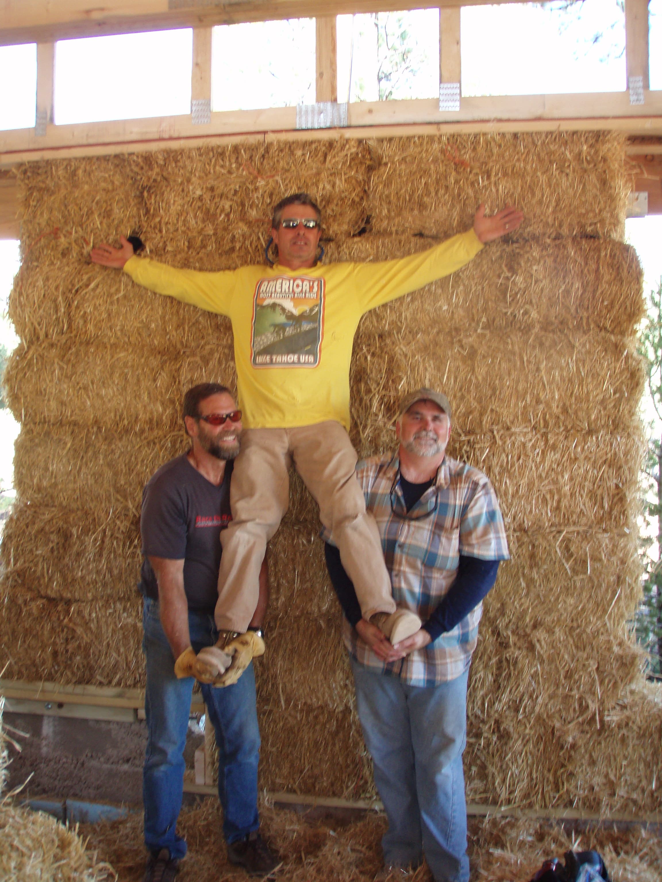 three men in front of a straw bale wall
