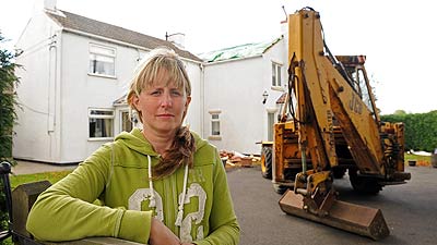 woman and backhoe in front of house