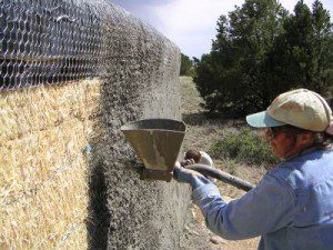 Woman Spraying plaster on straw bale walls