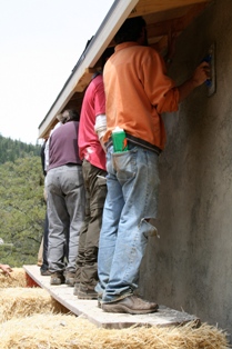 people plastering straw bale wall