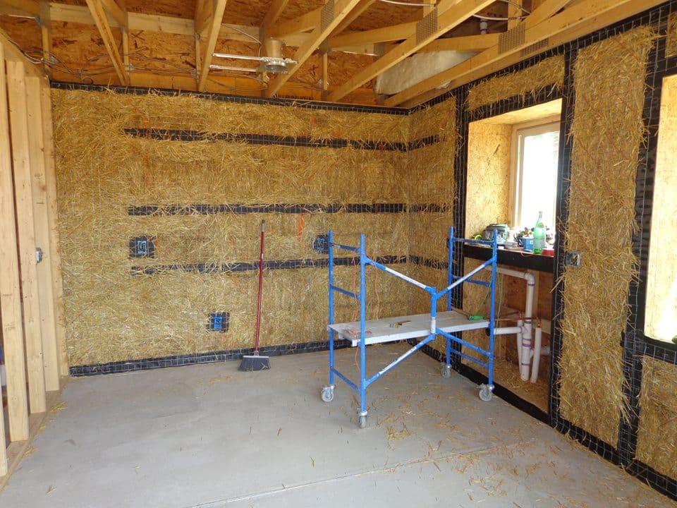 Strawbale building - bale wall with cabinet backers and electrical boxes installed